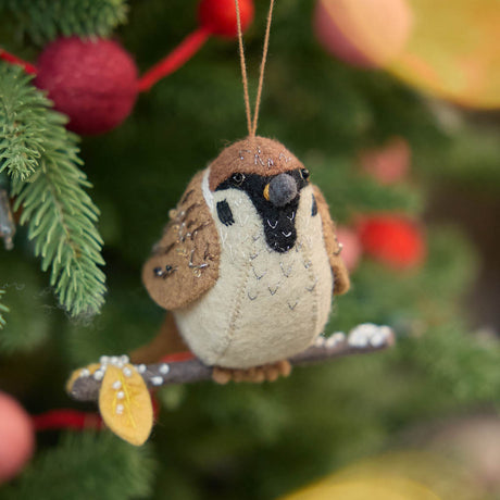 Celebrate the quiet beauty of everyday birds with our Sparrow Ornament. Small yet full of personality, this beloved garden bird is lovingly hand-felted from natural wool and perched on a delicate felt branch.
