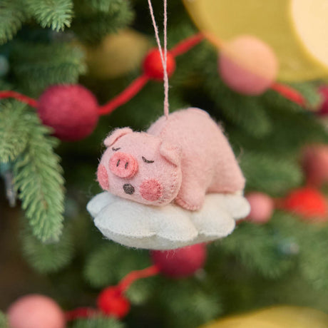 hanging on a glowing Christmas tree, sweet and serene, this adorable pig ornament rests peacefully on a soft cloud, capturing the gentle calm of a sleeping baby - irresistibly cute.&nbsp; With its rosy cheeks, tiny snout, and closed eyes, it brings a sense of warmth and quiet charm to any nursery or holiday setting. So cute it will make you squeal.&nbsp;