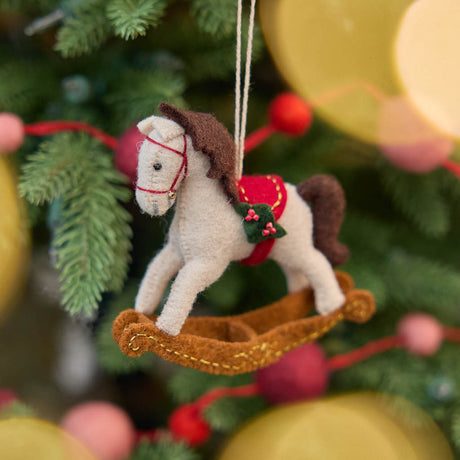 This charming rocking horse ornament captures the magic of childhood and holiday traditions. Crafted from natural wool felt, it features delicate stitching, a soft neutral palette, and subtle festive details that make it perfect for both baby gifting and seasonal décor.
