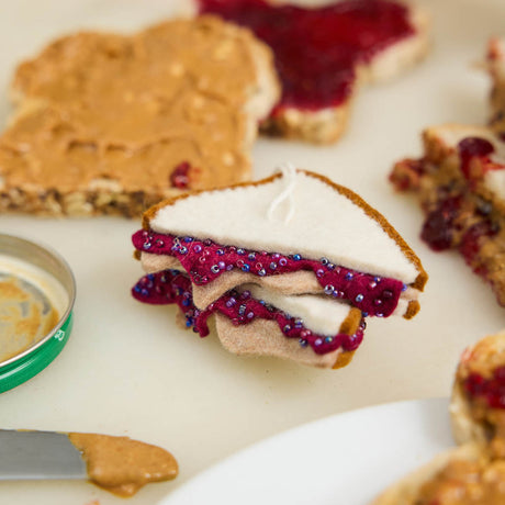 Bring a touch of lunchtime nostalgia to your holiday décor with our PB &amp; J Felt Ornament. This handcrafted design captures the classic peanut butter and jelly sandwich, complete with layered bread and vibrant jelly details.&nbsp; Go back in time with this classic sandwich ornament - think cafeteria lunches, hallway memories, dad packing your brown-paper bag lunch. This is a time-capsule!