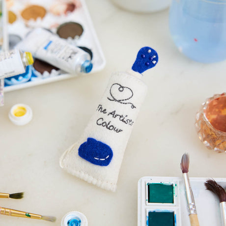 Add a splash of creativity to your holiday décor with our handcrafted Paint Tube Ornament. Designed for artists, makers, and color lovers, this charming felt ornament captures the playful essence of a classic paint tube—complete with a vibrant blue “paint” drop detail. On the back, intricate embroidery mimics a real paint label—complete with ‘Primary Blue #287’ markings and barcode-style details—adding an extra layer of realism and handcrafted charm.