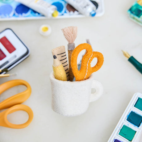 Bring the charm of the classroom and the drafting table to your holiday décor with our Pencil Cup Felt Ornament. This handcrafted design features a soft wool felt mug filled with iconic school and creative essentials—bright scissors, a pencil, a paintbrush, a fountain pen, and a ruler—capturing the everyday magic of learning and creativity.&nbsp;