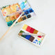 A small celebration of color in miniature form, our Paint Palette Ornament captures the familiar beauty of an artist’s workspace. Soft blocks of felted color sit alongside a tiny paintbrush with splashing embroidered brushstrokes, as if paused mid-creation.