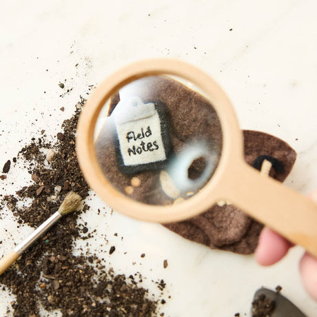 Unearth a piece of prehistoric wonder with our Felt Dinosaur Bones Ornament. Carefully handcrafted by skilled artisans using sustainable wool felt, this charming ornament features an excavation scene complete with partially uncovered dinosaur fossils, excavation tools, field notes, and scientific equipment.
