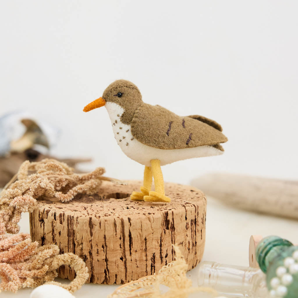 Bring a touch of the shoreline to your holiday décor with our delightful Spotted Sandpiper Ornament. Carefully handcrafted from eco-friendly wool felt, this charming bird captures the distinctive features of the beloved sandpiper, from its warm brown plumage and bright orange beak to its delicate spotted breast.