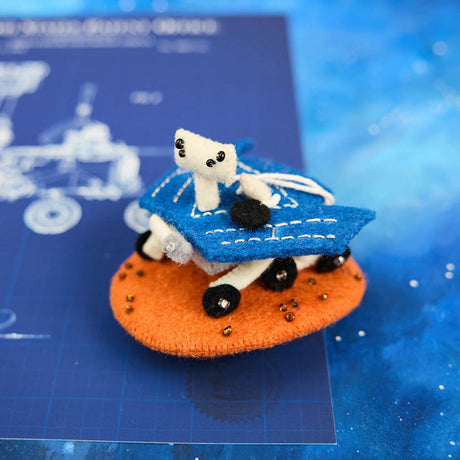 Explore the Red Planet with our handcrafted Mars Opportunity Rover Ornament, inspired by NASA’s legendary Mars Exploration Rover, affectionately known as "Oppy." Designed in soft wool felt with intricate handcrafted details, this ornament captures the iconic rover as it traverses the dusty Martian landscape in search of scientific discoveries.