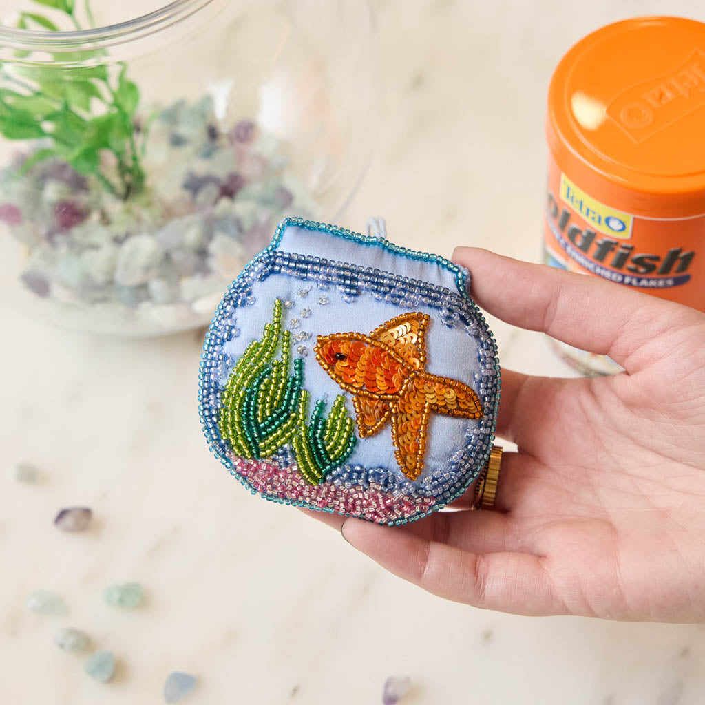 Make a splash with our whimsical Fishbowl Beaded Ornament! 🐠✨ This beautifully handcrafted ornament captures the charm of a beloved goldfish swimming peacefully through its miniature underwater world. Featuring a shimmering sequined goldfish, vibrant hand-beaded aquatic plants, and a sparkling fishbowl outlined with delicate glass beads, every detail is carefully stitched by hand to create a dazzling keepsake.