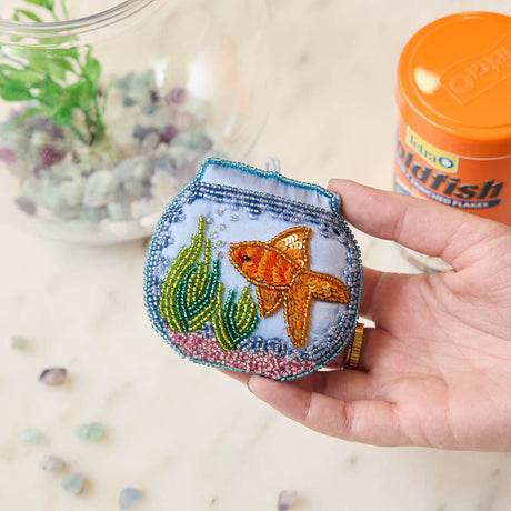 Make a splash with our whimsical Fishbowl Beaded Ornament! 🐠✨ This beautifully handcrafted ornament captures the charm of a beloved goldfish swimming peacefully through its miniature underwater world. Featuring a shimmering sequined goldfish, vibrant hand-beaded aquatic plants, and a sparkling fishbowl outlined with delicate glass beads, every detail is carefully stitched by hand to create a dazzling keepsake.