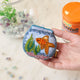 Make a splash with our whimsical Fishbowl Beaded Ornament! 🐠✨ This beautifully handcrafted ornament captures the charm of a beloved goldfish swimming peacefully through its miniature underwater world. Featuring a shimmering sequined goldfish, vibrant hand-beaded aquatic plants, and a sparkling fishbowl outlined with delicate glass beads, every detail is carefully stitched by hand to create a dazzling keepsake.
