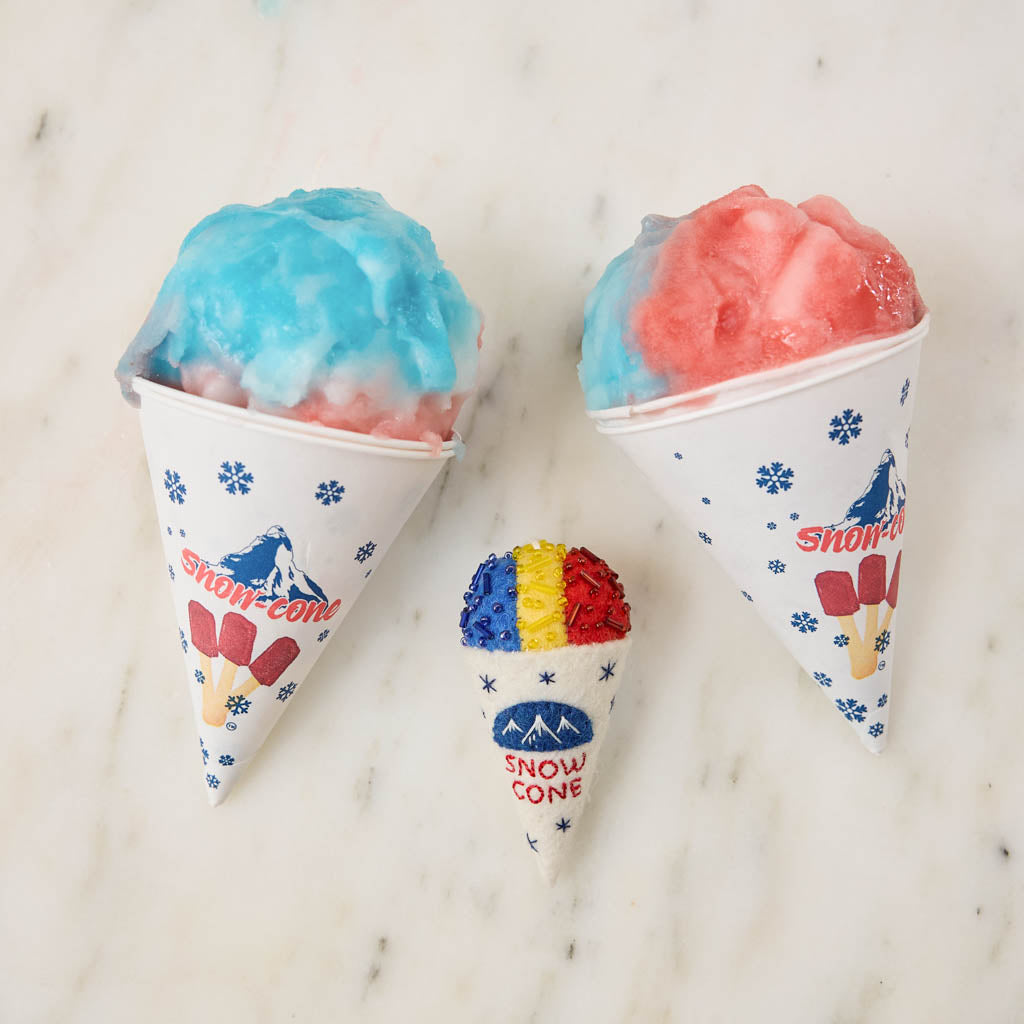 Cool off your Christmas tree with our Summer Snow Cone Ornament, a cheerful felt ornament inspired by one of summer’s most iconic frozen treats. Handcrafted by skilled artisans using traditional felting techniques, this whimsical ornament features a vibrant tri-color snow cone topped with sparkling bead accents that mimic crunchy ice crystals. The detailed white cone is embroidered with classic snow cone graphics and playful lettering, capturing the carefree spirit of amusement parks, beach vacations, and s