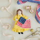 Celebrate the legendary maker associated with America’s first flag with our handcrafted Betsy Ross Ornament. Dressed in a bright colonial gown and holding the iconic early American flag, Betsy honors the spirit of independence, ingenuity, and handmade tradition.