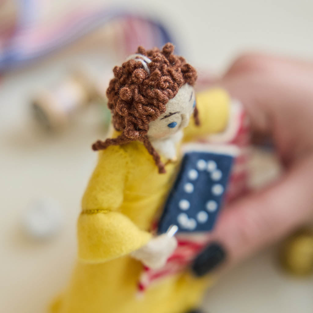 Celebrate the legendary maker associated with America’s first flag with our handcrafted Betsy Ross Ornament. Dressed in a bright colonial gown and holding the iconic early American flag, Betsy honors the spirit of independence, ingenuity, and handmade tradition.