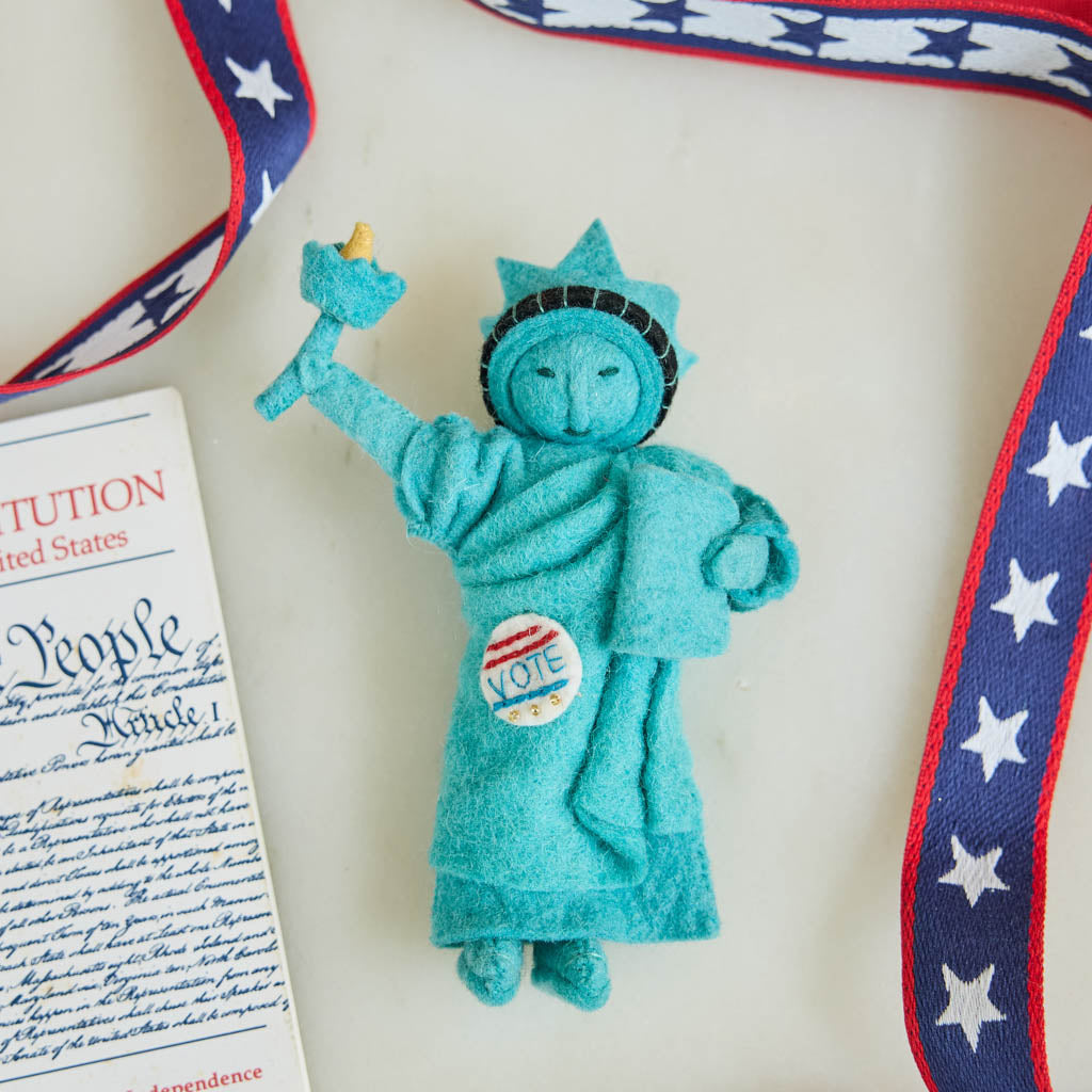 Celebrate the power of democracy with our handcrafted&nbsp;I Voted Lady Liberty Ornament from the Craftspring Semiquincentennial Collection. Inspired by the iconic Statue of Liberty, this felt ornament features Lady Liberty holding her torch and tablet while proudly displaying an “I Voted” badge—symbolizing freedom, participation, and the enduring values of American democracy.