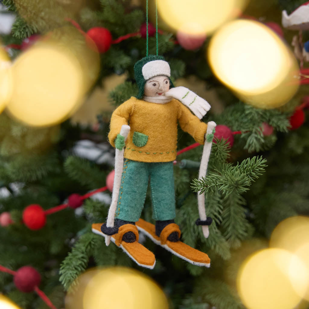 Our Cross-Country Skier Ornament is a handmade wool felt Christmas decoration featuring a warmly dressed skier with ski poles, perfect for Nordic skiing enthusiasts, outdoor adventurers, and winter-inspired holiday décor.