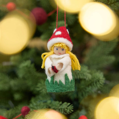 A magical little child of the forest, bringing good fortune, woodland wonder, and a sprinkle of fairy-tale enchantment into your home all year round! This sweet little red Amanita mushroom girl ornaments features a bright red felted mushroom cap, dotted with delicate white spots, and a skirt hemmed with felted green grasses. 