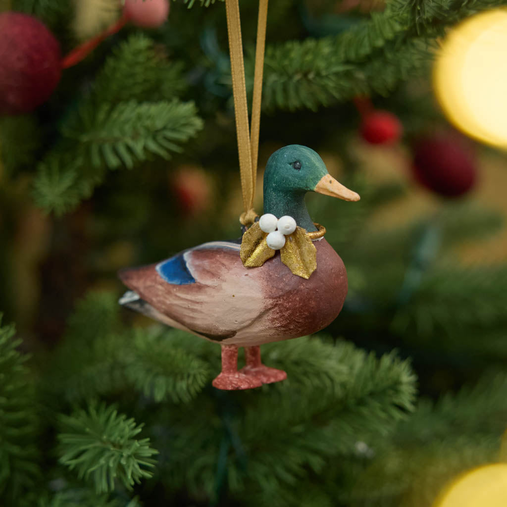 A vintage-inspired Mallard Duck Resin Ornament, hand-painted in the Philippines with a golden metal holly necklace and satin hanging ribbon.