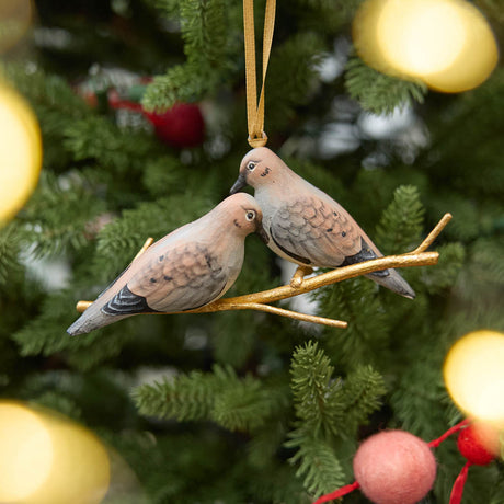 Two little doves, perched side by side. Our Mourning Doves Ornament captures one of nature’s sweetest pairings, with two beautifully hand-painted birds resting together on a delicate gold-toned metal branch.