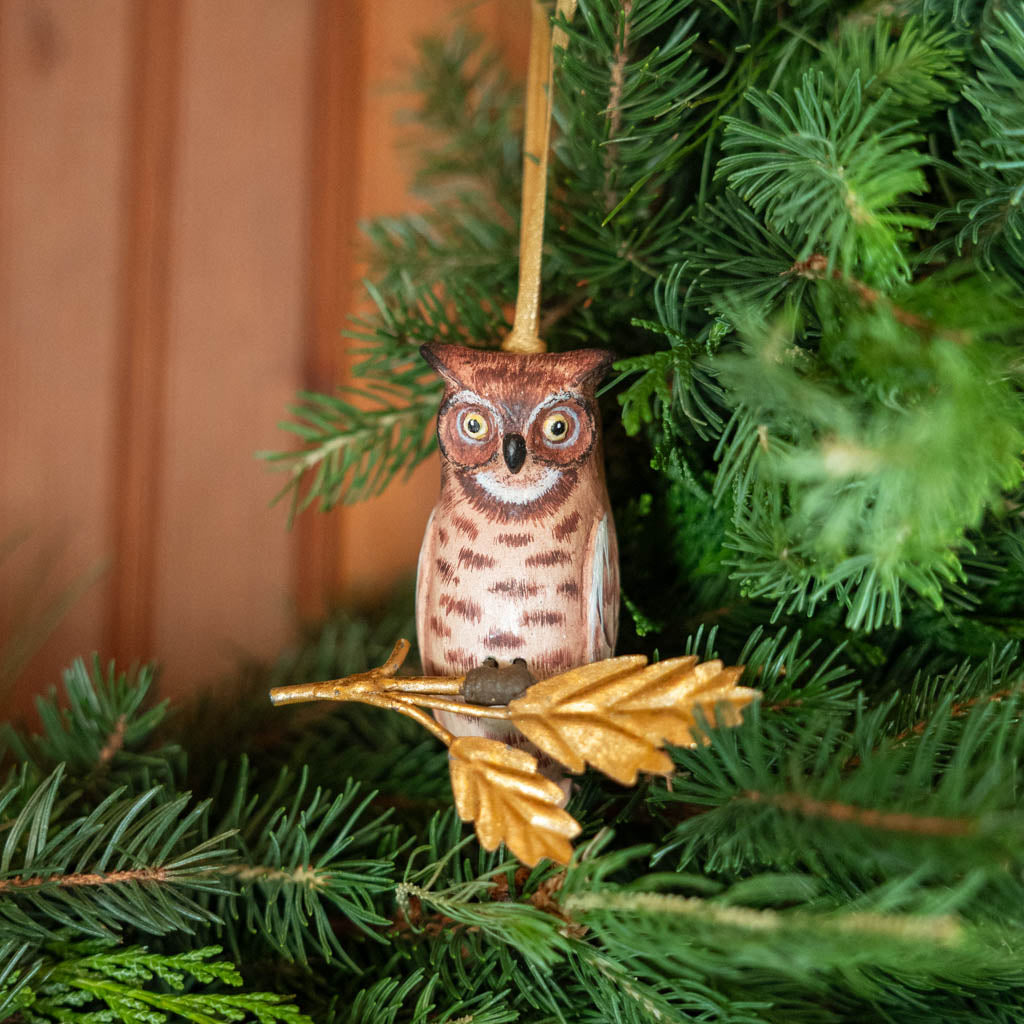 A vintage-inspired Great Horned Owl Resin Ornament, hand-painted in the Philippines and perched on a golden metal oak branch with sculpted leaves.