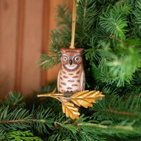 A vintage-inspired Great Horned Owl Resin Ornament, hand-painted in the Philippines and perched on a golden metal oak branch with sculpted leaves.