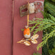 A vintage-inspired Robin Ornament, featuring a hand-painted red-breasted bird perched on a golden metal holly branch with white berries.