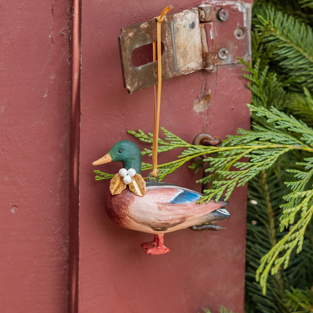 A vintage-inspired Mallard Duck Resin Ornament, hand-painted in the Philippines with a golden metal holly necklace and satin hanging ribbon.