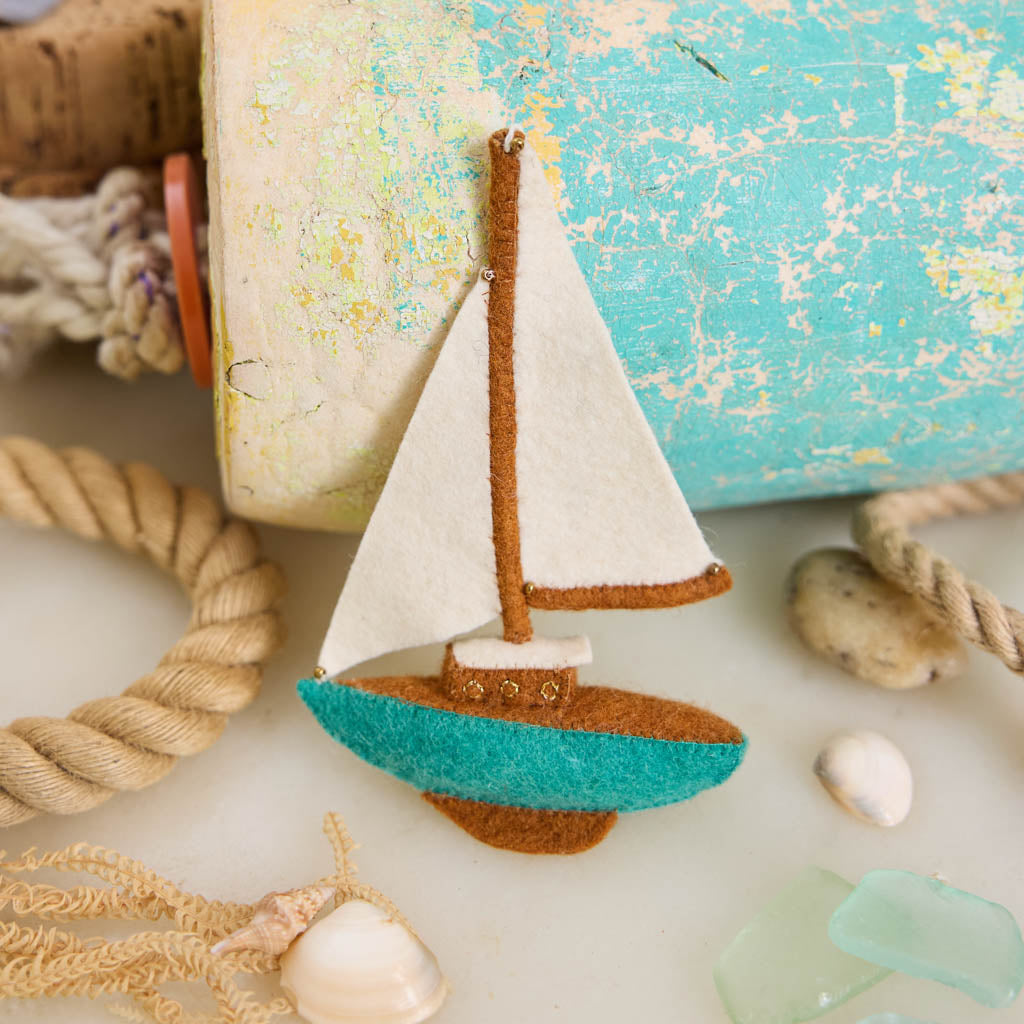 Set sail for holiday memories with our handcrafted Sailboat Ornament, a charming tribute to life on the water. Featuring crisp white sails, a warm wood-toned mast and deck, and a sea-glass-inspired turquoise hull, this classic sailboat captures the quiet beauty of coastal living and the freedom of open water.