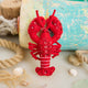 Commemorate the bounty of the northeastern seaboard with our handcrafted Bejeweled Red Lobster Ornament, designed to bring the spirit of coastal Maine to your home. Crafted from vibrant red felt and embellished with sparkling beads and sequins, this festive lobster ornament catches the light beautifully, adding texture, shimmer, and whimsical seaside charm to your holiday décor.
