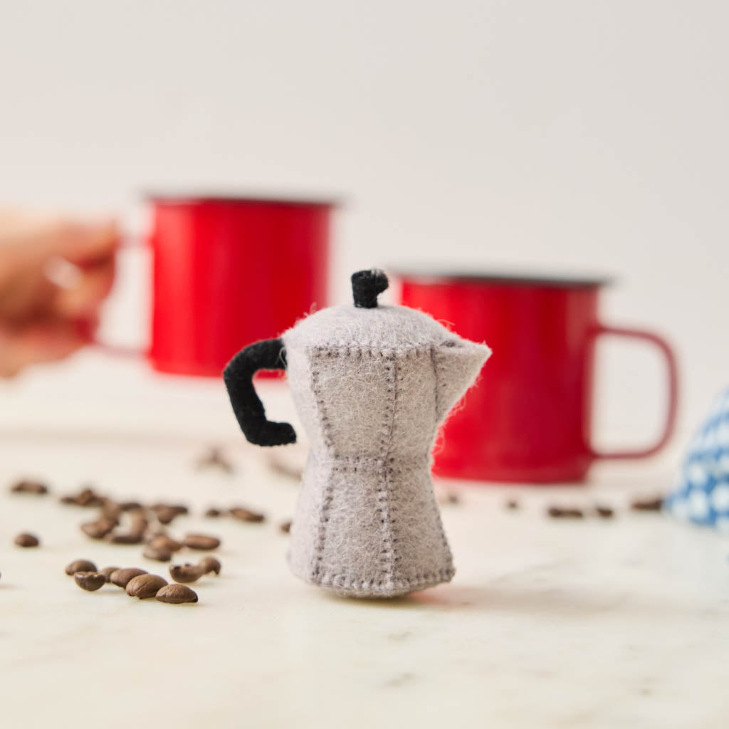 Handcrafted from natural wool felt, this charming ornament is inspired by the classic stovetop camping percolator—a beloved companion for generations of campers, hikers, RV travelers, and cabin lovers. Its timeless silhouette, soft neutral tones, and handcrafted stitching evoke memories of peaceful mornings surrounded by towering pines, fresh mountain air, and the sounds of nature waking up.