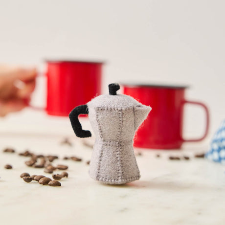 Handcrafted from natural wool felt, this charming ornament is inspired by the classic stovetop camping percolator—a beloved companion for generations of campers, hikers, RV travelers, and cabin lovers. Its timeless silhouette, soft neutral tones, and handcrafted stitching evoke memories of peaceful mornings surrounded by towering pines, fresh mountain air, and the sounds of nature waking up.