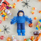 A handmade felt Monster Trick-or-Treater Ornament featuring a child dressed in a fuzzy blue monster costume and carrying a miniature jack-o’-lantern candy bucket.