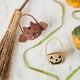 A hand-crocheted raffia Mini Bat Basket featuring playful wings, pointed ears, tiny fangs, and a sweet embroidered face for Halloween treats, treasures, and imaginative play.