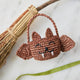 A hand-crocheted raffia Mini Bat Basket featuring playful wings, pointed ears, tiny fangs, and a sweet embroidered face for Halloween treats, treasures, and imaginative play.
