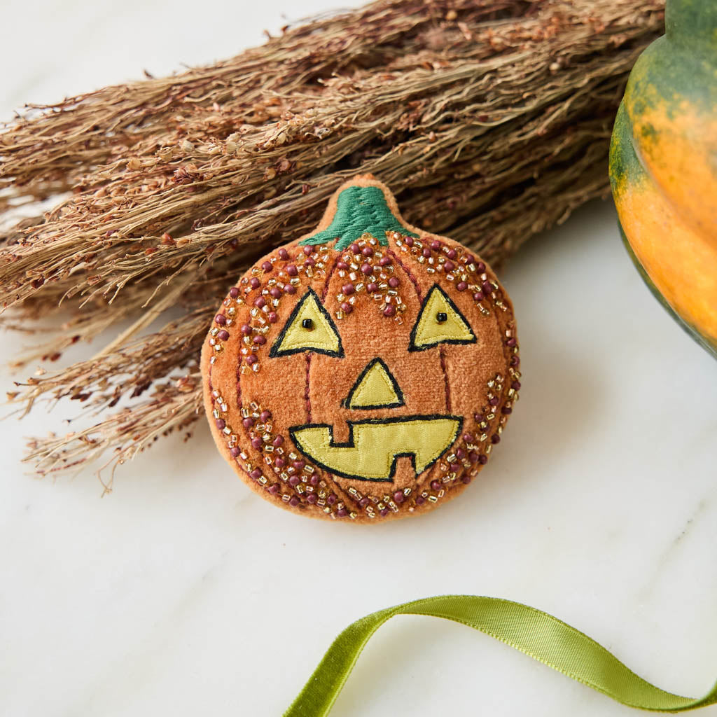 A vintage-inspired handmade beaded Jack O’Lantern Ornament featuring a smiling embroidered pumpkin face on one side and festive “Trick or Treat” detailing on the reverse.