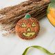 A vintage-inspired handmade beaded Jack O’Lantern Ornament featuring a smiling embroidered pumpkin face on one side and festive “Trick or Treat” detailing on the reverse.