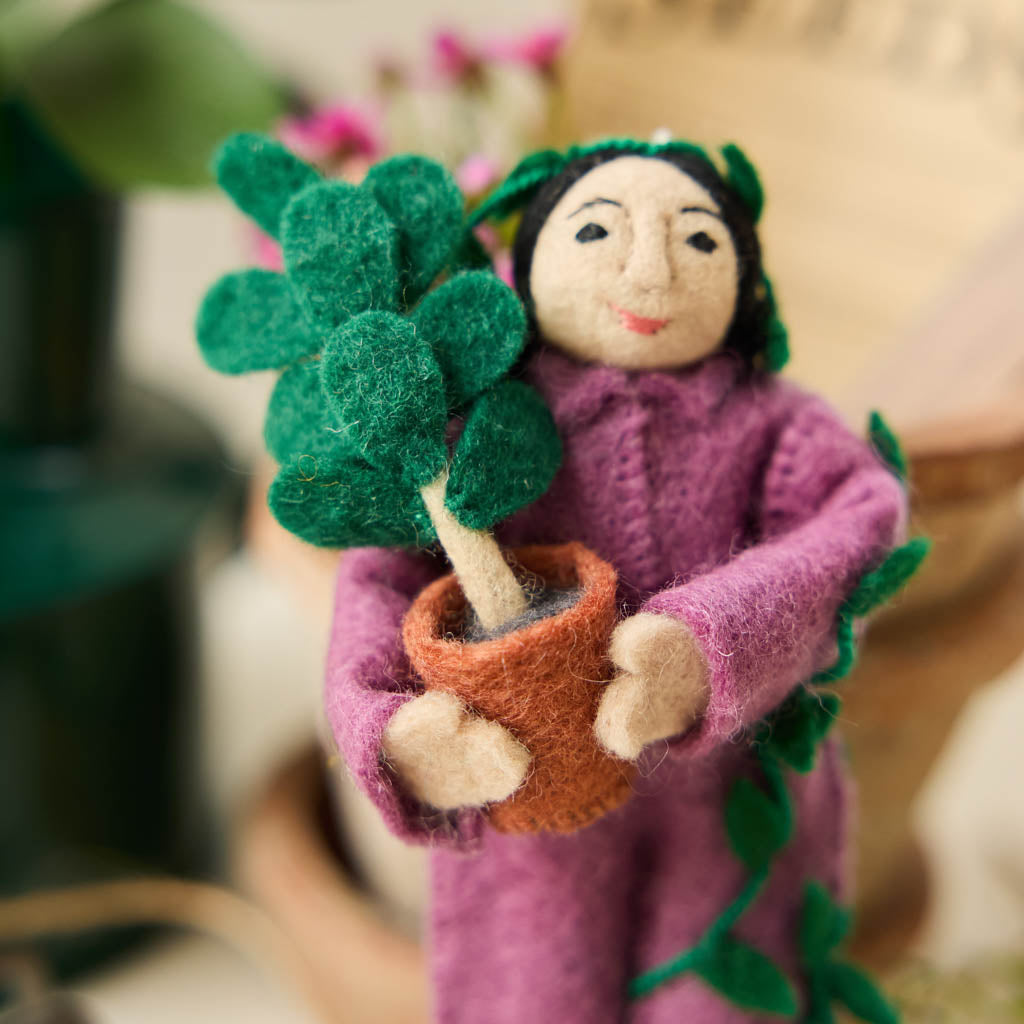 For the person who always has room for just one more plant, our Plant Parent Ornament celebrates the love, care, and wonderfully leafy obsession of keeping a home full of green things. Handcrafted from natural wool by skilled artisans, this whimsical felt ornament features a proud plant parent dressed in purple and happily surrounded by an abundance of potted greenery.