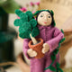 For the person who always has room for just one more plant, our Plant Parent Ornament celebrates the love, care, and wonderfully leafy obsession of keeping a home full of green things. Handcrafted from natural wool by skilled artisans, this whimsical felt ornament features a proud plant parent dressed in purple and happily surrounded by an abundance of potted greenery.