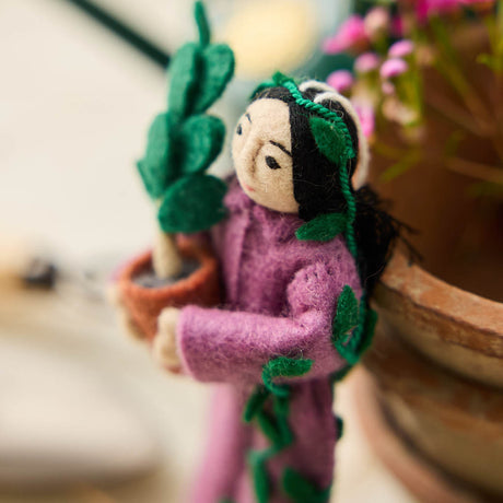For the person who always has room for just one more plant, our Plant Parent Ornament celebrates the love, care, and wonderfully leafy obsession of keeping a home full of green things. Handcrafted from natural wool by skilled artisans, this whimsical felt ornament features a proud plant parent dressed in purple and happily surrounded by an abundance of potted greenery.