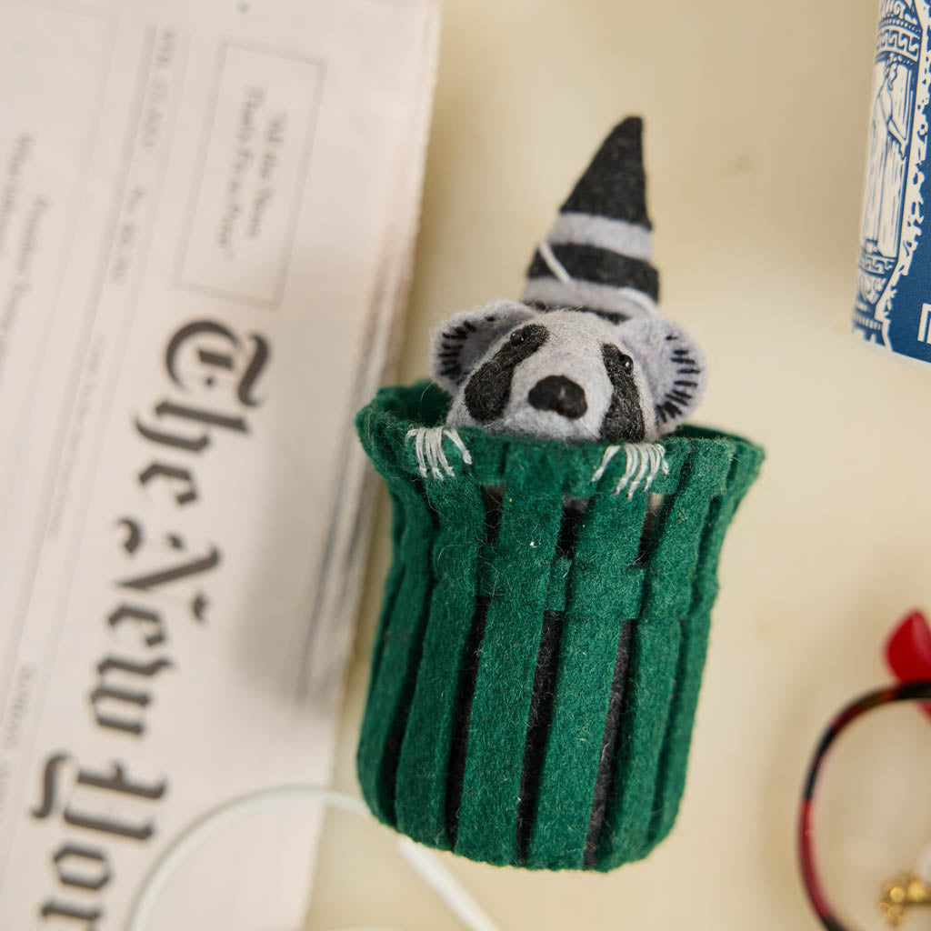 Every city has its unofficial mascot, and New York's just might be the mischievous raccoon. Meet our Trash Raccoon Ornament, peeking curiously from inside a classic green city trash can with the sweetest little face you've ever seen. Don't worry—this tiny trash panda is all charm and absolutely no trouble.