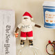 Celebrate Christmas in the Big Apple with our handmade NYC Santa Ornament, featuring a deep brown Santa dressed like a true New Yorker in an NYC tee and sneakers, with a classic slice of New York pizza in hand.