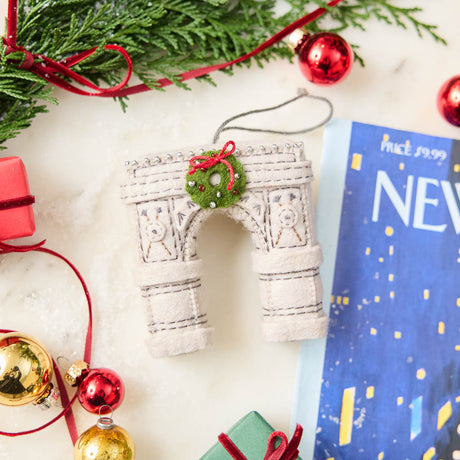  Our Grand Arch Ornament captures that timeless landmark, beautifully adorned with a festive holiday wreath for an extra touch of seasonal cheer.

Carefully handcrafted with embroidered architectural details, sculptural felt columns, delicate bead accents, and a miniature wreath tied with a bright red bow, this ornament celebrates both the elegance of the famous arch and the magic of Christmas in New York. 