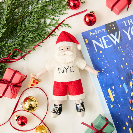 Celebrate Christmas in the Big Apple with our handmade NYC Santa Ornament, featuring Santa dressed like a true New Yorker with an NYC tee and a classic slice of New York pizza.

Who says Santa only runs on milk and cookies? After a busy night delivering gifts across the five boroughs, he's treating himself to a well-earned slice of New York pizza.