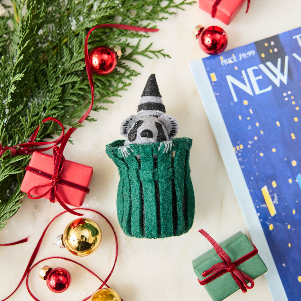 Every city has its unofficial mascot, and New York's just might be the mischievous raccoon. Meet our Trash Raccoon Ornament, peeking curiously from inside a classic green city trash can with the sweetest little face you've ever seen. Don't worry—this tiny trash panda is all charm and absolutely no trouble.