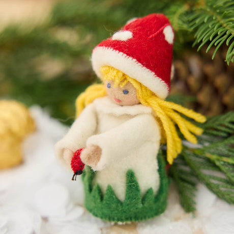 A magical little child of the forest, bringing good fortune, woodland wonder, and a sprinkle of fairy-tale enchantment into your home all year round! This sweet little red Amanita mushroom girl ornaments features a bright red felted mushroom cap, dotted with delicate white spots, and a skirt hemmed with felted green grasses. 