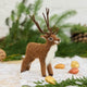 A small felted wool reindeer figurine with brown fur, a white chest, and brown antlers, Soft, fuzzy, and full of woodland wonder, our Fuzzy Reindeer Ornament captures the quiet magic of the holiday season. With its beautiful tall antlers, sweet expression, and irresistibly fluffy coat, this darling little reindeer looks as though it has wandered straight out of an enchanted winter forest.