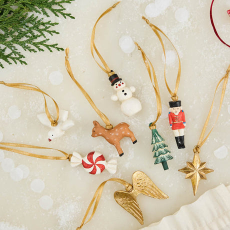 A set of eight hand-painted mini Christmas ornaments featuring nostalgic holiday icons, each finished with a golden satin ribbon and tucked into a reusable cotton gift pouch. Made to last and keep forever.