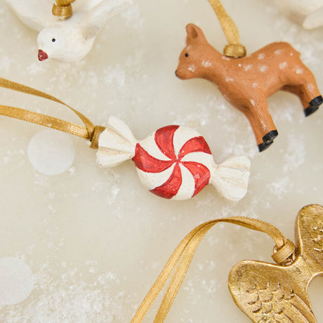 A set of eight hand-painted mini Christmas ornaments featuring nostalgic holiday icons, each finished with a golden satin ribbon and tucked into a reusable cotton gift pouch. Made to last and keep forever.