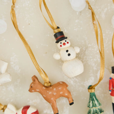 A set of eight hand-painted mini Christmas ornaments featuring nostalgic holiday icons, each finished with a golden satin ribbon and tucked into a reusable cotton gift pouch. Made to last and keep forever.