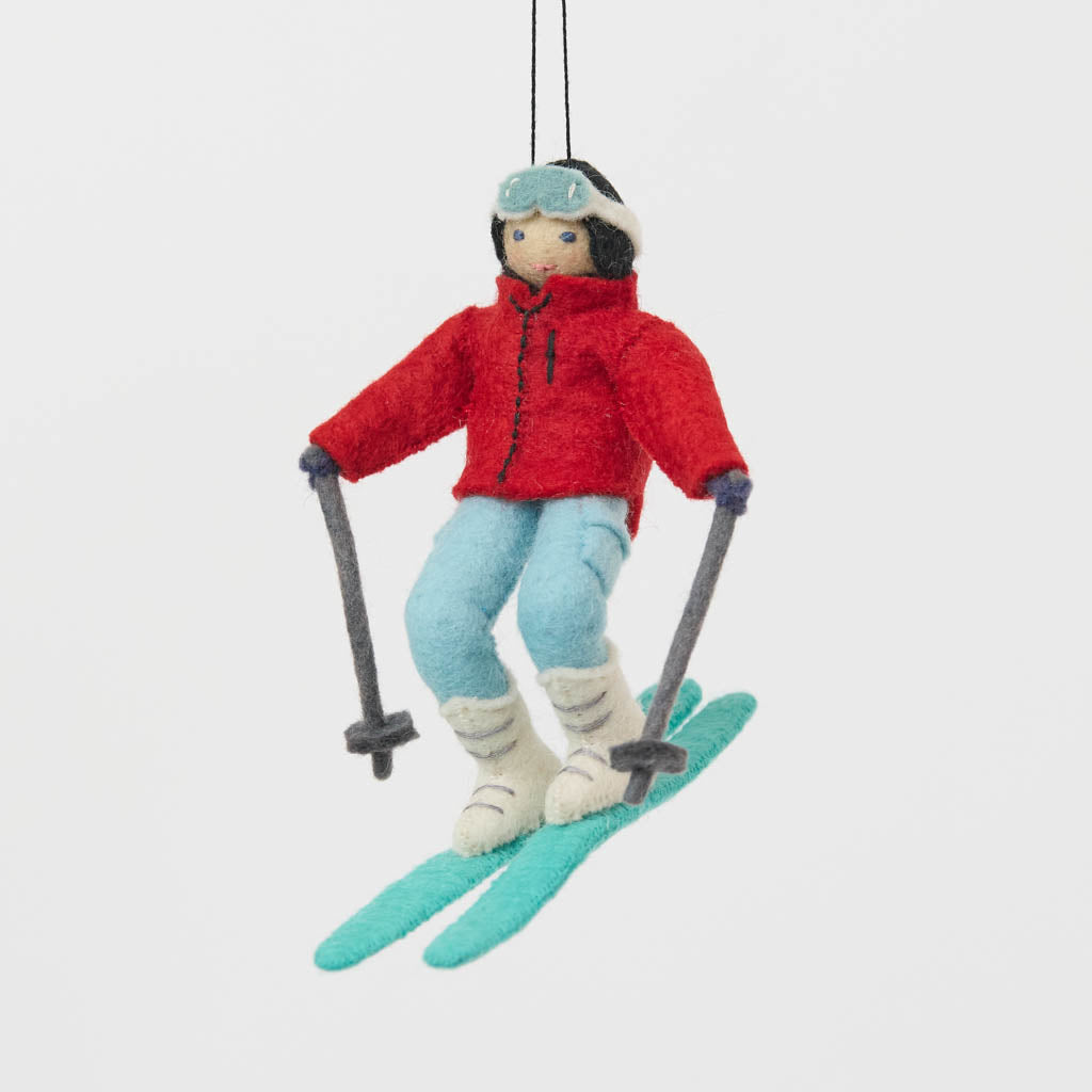Our Alpine Skier Ornament is ready to carve through the holiday season in style. Dressed in a bright red ski jacket, powder-blue pants, and matching goggles, this spirited skier comes complete with turquoise skis and poles, capturing the thrill of a perfect day on the mountain.