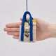 Handmade felt Beach Bag ornament from Craftspring shown held in front of a hand to highlight its size—filled with summer essentials like a beach ball, towel, flip flops, sunscreen, and sunglasses, ethically crafted by artisans in India using sustainable wool.