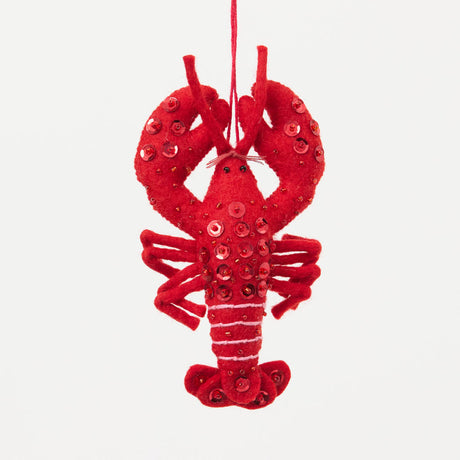 Commemorate the bounty of the northeastern seaboard with our handcrafted Bejeweled Red Lobster Ornament, designed to bring the spirit of coastal Maine to your home. Crafted from vibrant red felt and embellished with sparkling beads and sequins, this festive lobster ornament catches the light beautifully, adding texture, shimmer, and whimsical seaside charm to your holiday décor.